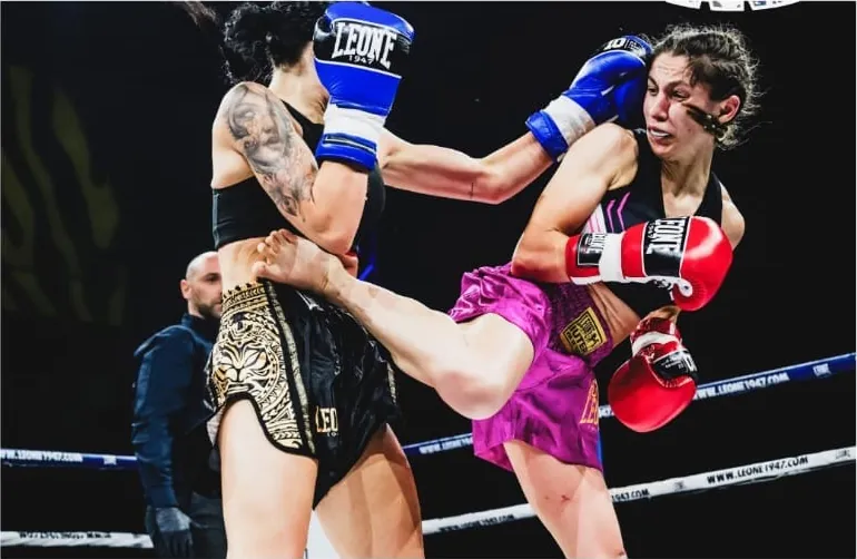Alessia Muroni con i guantoni rossi e i pantaloncini fucsia mette a segno un calcio durante un incontro