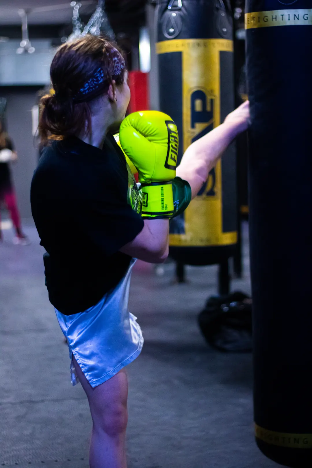 Allieva di kickboxing calcia il sacco con i guantoni verdi