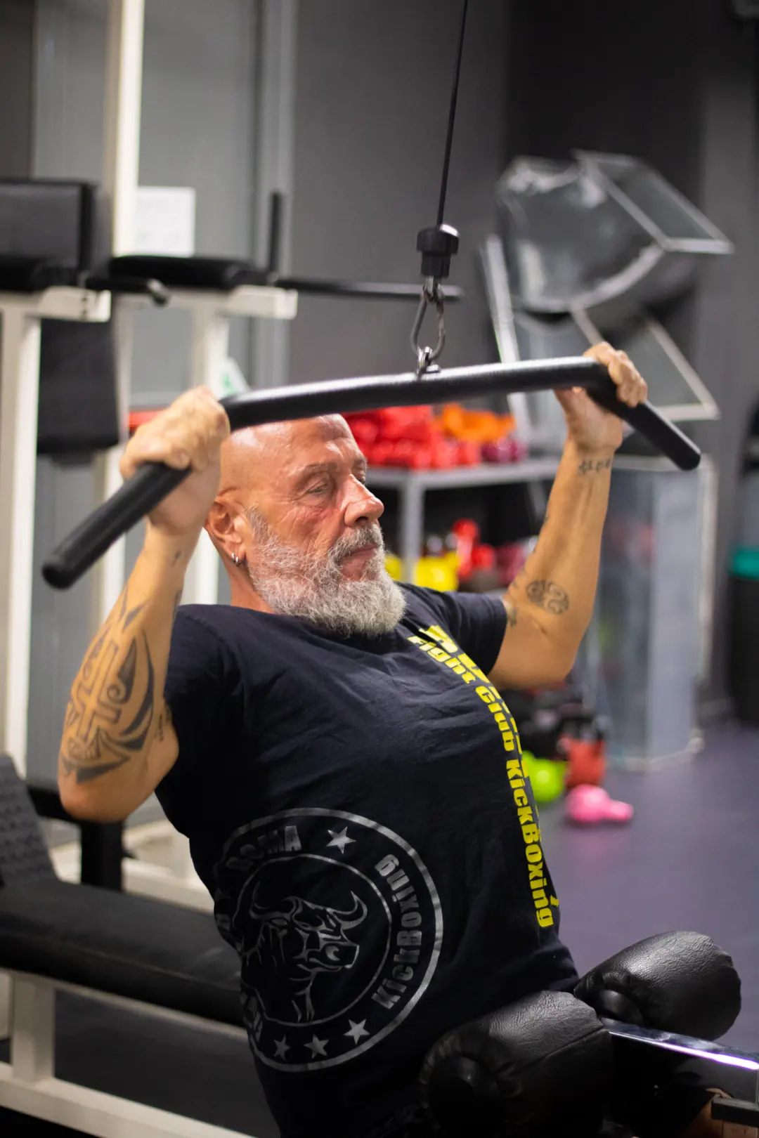 Atleta over 50 alla lat machine nella sala pesi