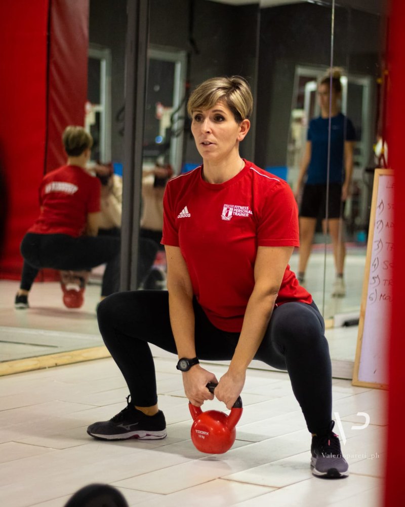 Donatella Vecchioni durante un esercizio di squat con kettlebell, maglia FIPE Fitness Personal Trainer